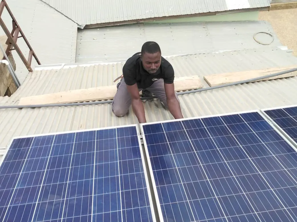 Technician fitting solar panels to a site roof